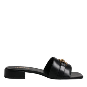 Sandalias planas sin cordones con placa del logotipo de cuero negro de Versace